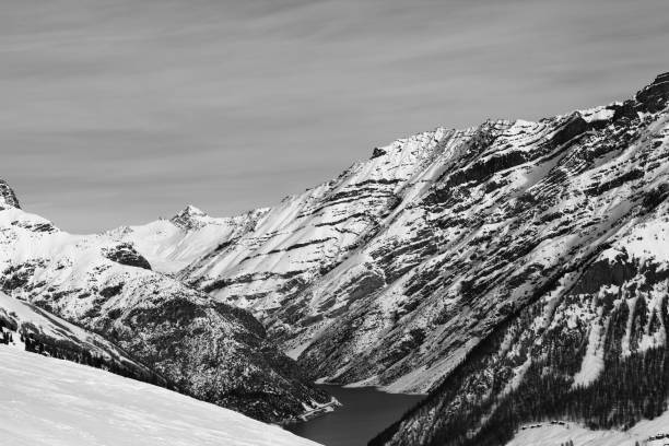istock Off-piste ski slope, snowy high mountains with forest, big lake 1205627302