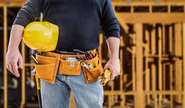 istock Contractor With Tool Belt and Hard Hat In Front of Wood Framing Construction Site 1205632066