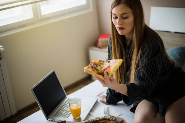 istock A young girl eating pizza in bed 1205634615