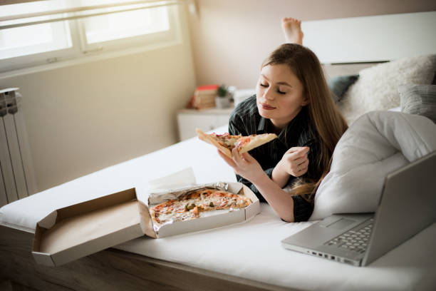 istock A young girl eating pizza in bed 1205635176