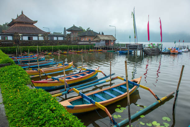 grupo de kayak balineso tradicional llamado "jukung" flotando en la zona del templo pura ulan danu bratan a orillas del lago bratan, bali, indonesia. - jukung fotografías e imágenes de stock