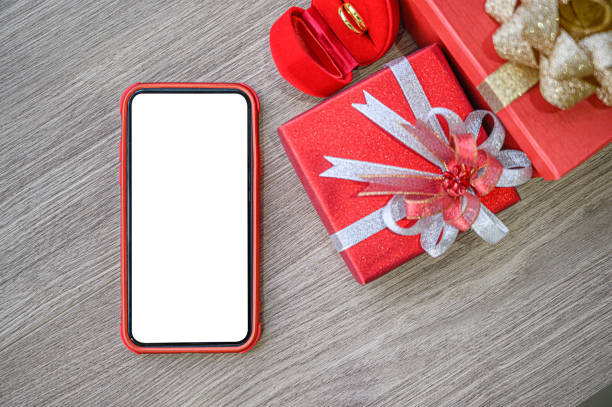 istock White blank screen of phone with gift boxes and ring on wooden background. 1205641205