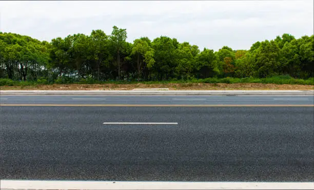 Photo of New asphalt roads, trees under blue sky and white clouds