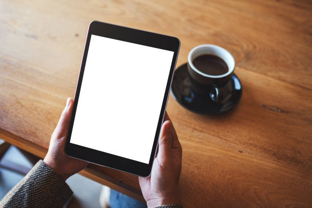 istock hands holding black tablet pc with blank white screen with coffee cup on wooden table 1205644079
