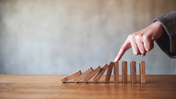 istock a finger try to stopping falling wooden dominoes blocks for business solution concept 1205644111
