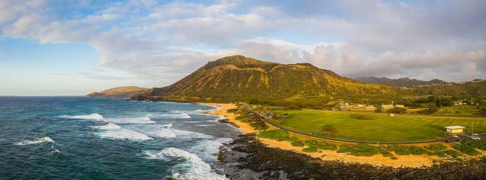 Panorama of Koko Head crater taken from a drone in Hawaii with both a rocky and a sandy beach with the incoming surf from the Pacific Ocean in morning light.