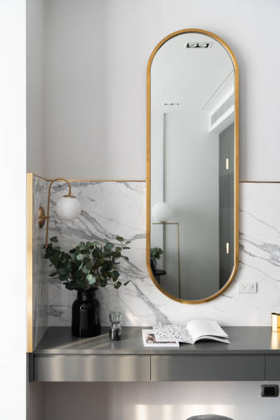 istock Bedroom working corner decorated with gold stainless mirror and artificial plant in glass vase on gray spray-painted  working table with  marble wall background /apartment interior /copyspace 1205646496