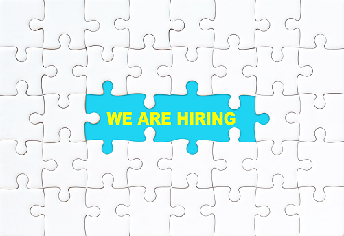 We are hiring concept. White jigsaw puzzle with word and blue background