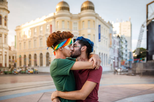 カーニバルで路上でキスゲイカップル - gay man homosexual men kissing ストックフォトと画像