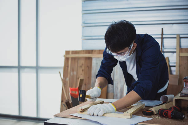 istock Asian man Carpenter working with technical drawing or blueprint construction paper lying on a workshop with carpentry tools and wood at home 1205651617