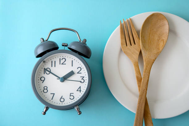 tiempo para perder peso, control de comer o tiempo para el concepto de dieta, reloj despertador con decoración de concepto de herramienta saludable sobre un fondo azul - ayuno intermitente fotografías e imágenes de stock