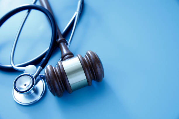 医療と法律産業の交差を表す青い背景にガヴェルと聴診器。