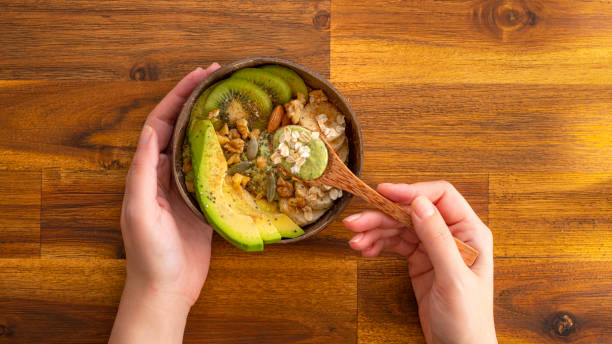 Healthy green vegan snack in a coconut bowl Healthy, plant based foods; avocado, kiwi, bananas, almond and walnuts in a coconut bowl. Embrace Protein stock pictures, royalty-free photos & images