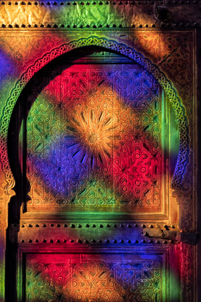 Traditional, old, moroccan door with wood carvings, with multicolored reflections from colored glass window. stock photo