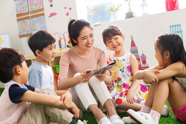 Kindergarten teacher tells the children stories Kindergarten teacher tells the children stories chinese ethnicity stock pictures, royalty-free photos & images