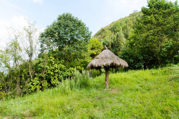 The outdoor massage lounger under the thatch roof in the Balinese lush garden with blue sky and white clouds in background