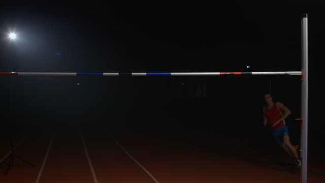Slow motion: Male high jumper jumping over the bar, success