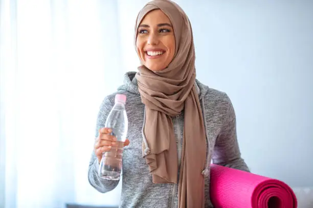 Islamic woman preparing for workout. Young muslim woman ready to running. Islamic woman resting and drinking water. Portrait of muslim woman likes her active life
