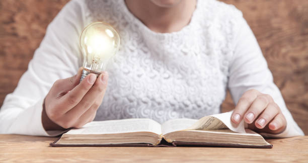 istock Girl holding light bulb and reading book. Knowledge, Creative, Wisdom 1205684534