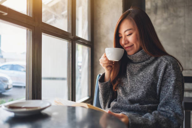 istock a beautiful woman reading a book while drinking coffee in the morning 1205684631