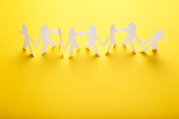 istock Paper chain people on yellow background 1205685602