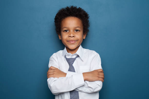 istock Little black child boy with arms crossed on blue background 1205689071