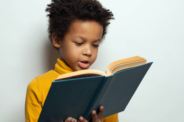 istock Little African American child boy reading a book on white background. Black kid student portrait 1205689097