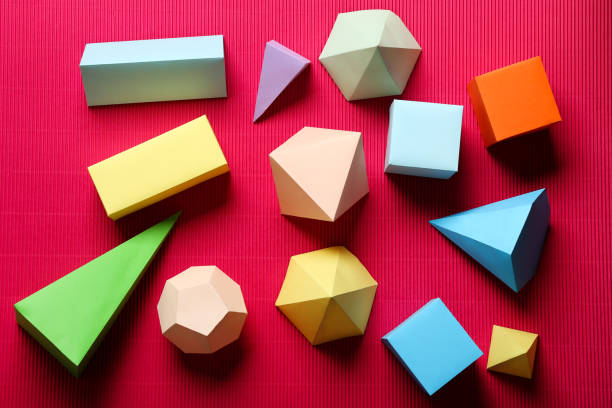 istock Colorful paper geometric figures on red background 1205693694