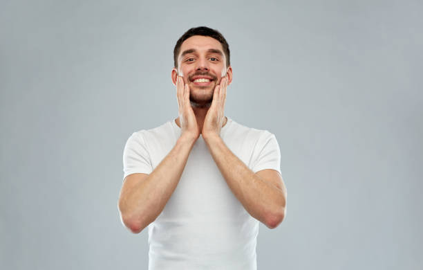 istock happy young man applying aftershave to face 1205693700