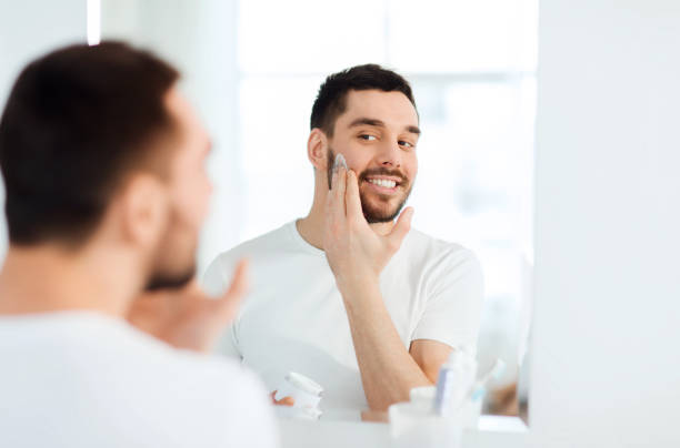 istock happy young man applying cream to face at bathroom 1205693732