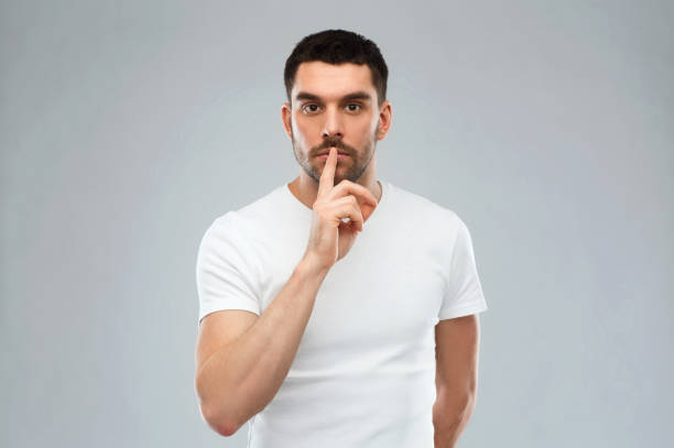 istock young man making hush sign over gray background 1205693863