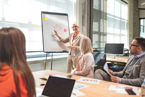 istock Mature CEO giving a business presentation through white board in board room. 1205695153