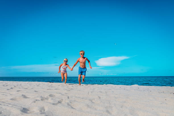 istock happy boy and girl running on beach 1205695261