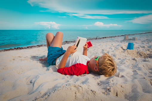 boy reading book at sand beach, kid learning on sea vacation