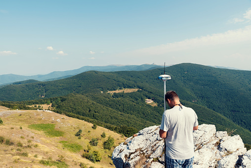 Engineer using GPS surveying equipment in mountain during the summer Selective focus