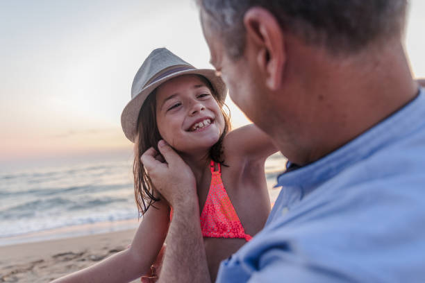 istock Joyful child with summer hat smiling to her dad on the beach 1205697866