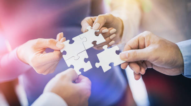 istock A group of business people assembling jigsaw puzzle. 1205699330