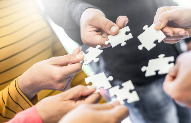 istock A group of business people assembling jigsaw puzzle. 1205699397