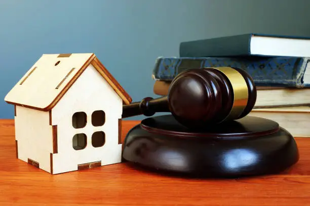 Photo of Property law concept. Gavel and tiny home on the desk.