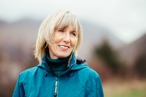 Mature woman portrait in Glencoe, Scotland. The out of focus background is the entrance to the glen.