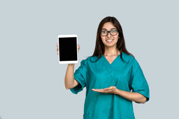 jeune femme indienne indienne infirmière professionnelle docteur féminin porter uniforme vert montrent tablette numérique maquette jusqu’à l’écran vide vide vide blanc annoncent le concept de technologie d’application de soin médical d’isolem - indian ethnicity audio photos et images de collection