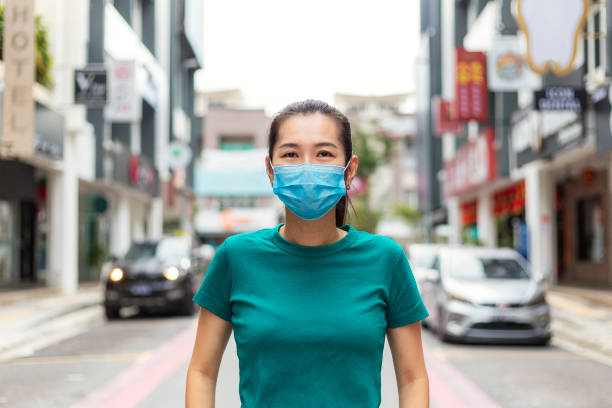 young woman wearing protective face mask in city for protection from cold and flu and viruses. - swine flu fotos imagens e fotografias de stock