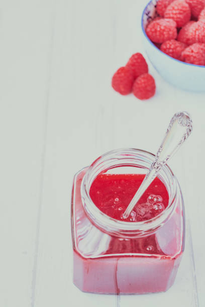 istock Raspberry jam served in a glass jar and spoon. 1205707012