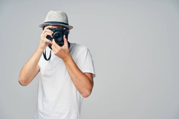 istock Young man taking picture with analog camera isolated on grey background 1205708802