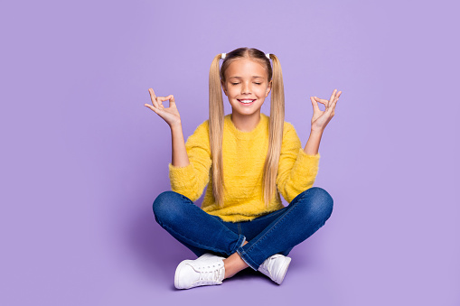 Full length photo of positive cheerful kid sit legs crossed folded train, yoga meditate show om sign wear yellow casual style clothing isolated over violet color background