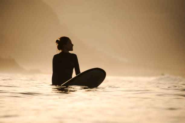 Silhouette of a surfer girl in the waters Silhouette of a fit surfer girl with hair bun in the waters black woman hair bun stock pictures, royalty-free photos & images