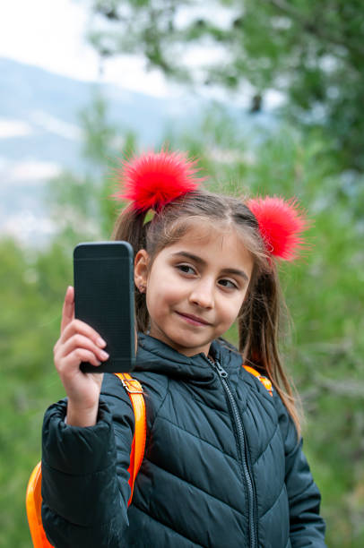 istock Littel girl using mobile phone by garden 1205717825