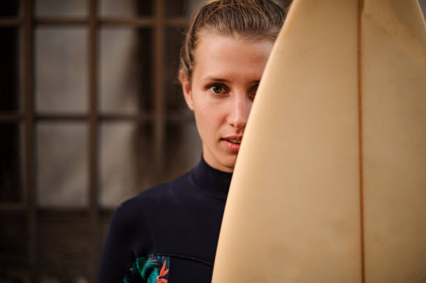 Surfer girl hides her face behind surfboard