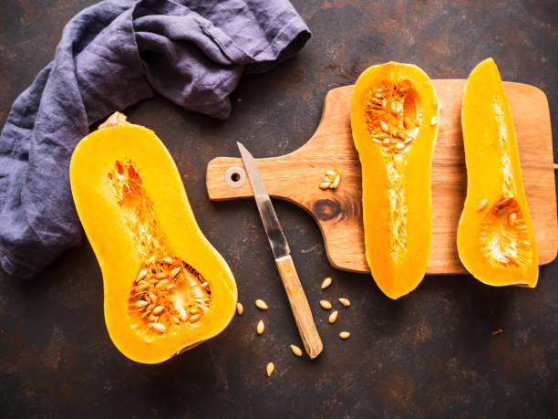 istock Half butternut squash on a wooden cutting board with knife, top view 1205720644