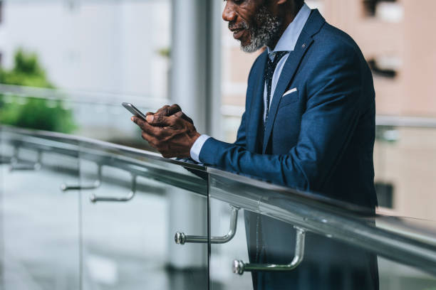 istock African Businessman Standing Outdoors and Typing on a Cell Phone 1205721074